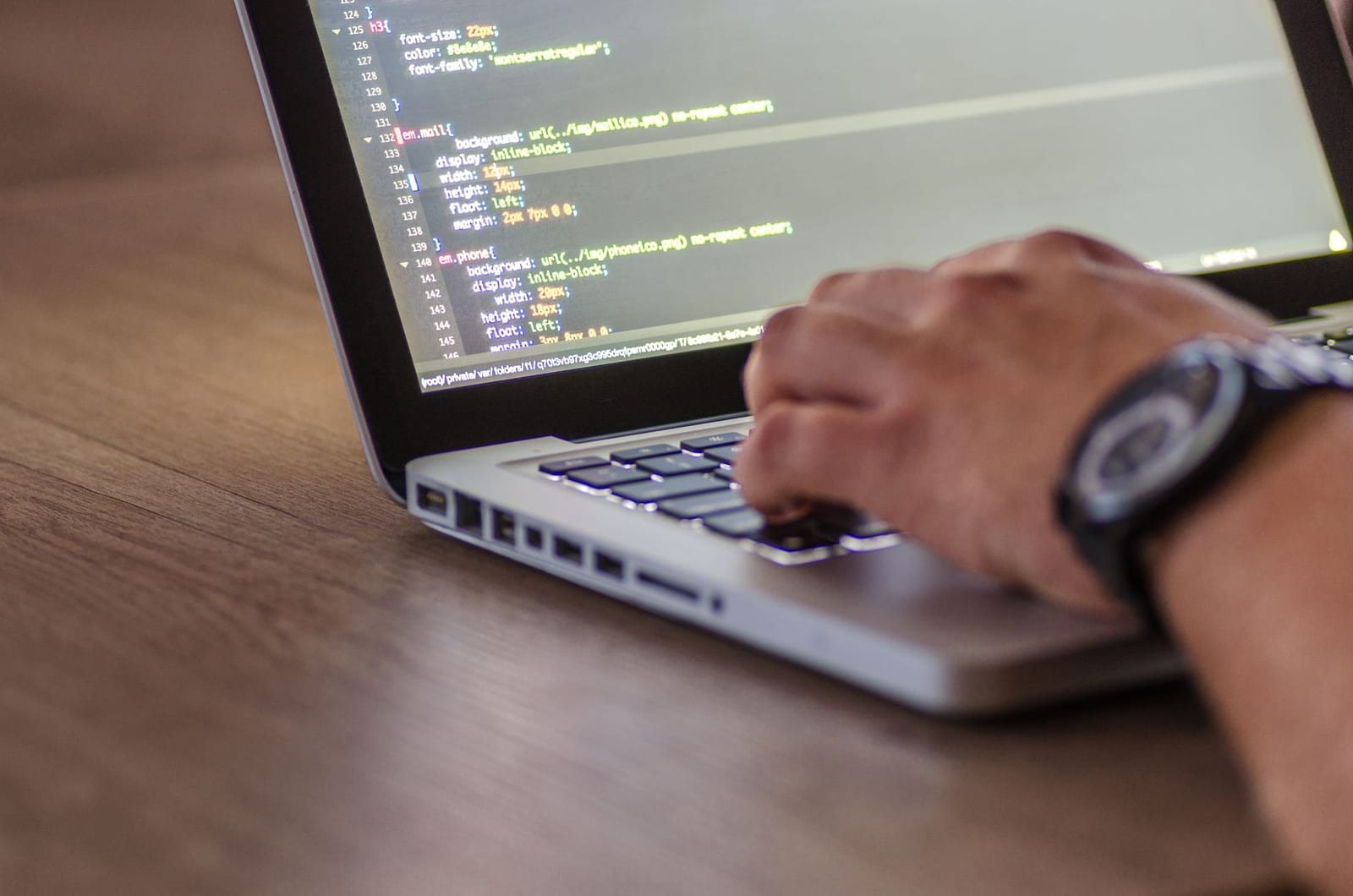 コードが表示された画面とノートパソコンを操作する手のアップ