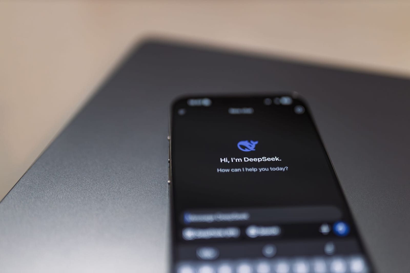 ノートパソコンの上に置かれDeepSeek画面を表示するスマホ