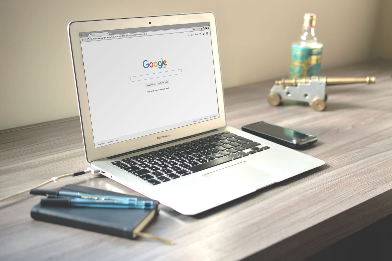木製デスクにGoogle検索画面を開いたノートパソコンとスマートフォンが置かれた様子