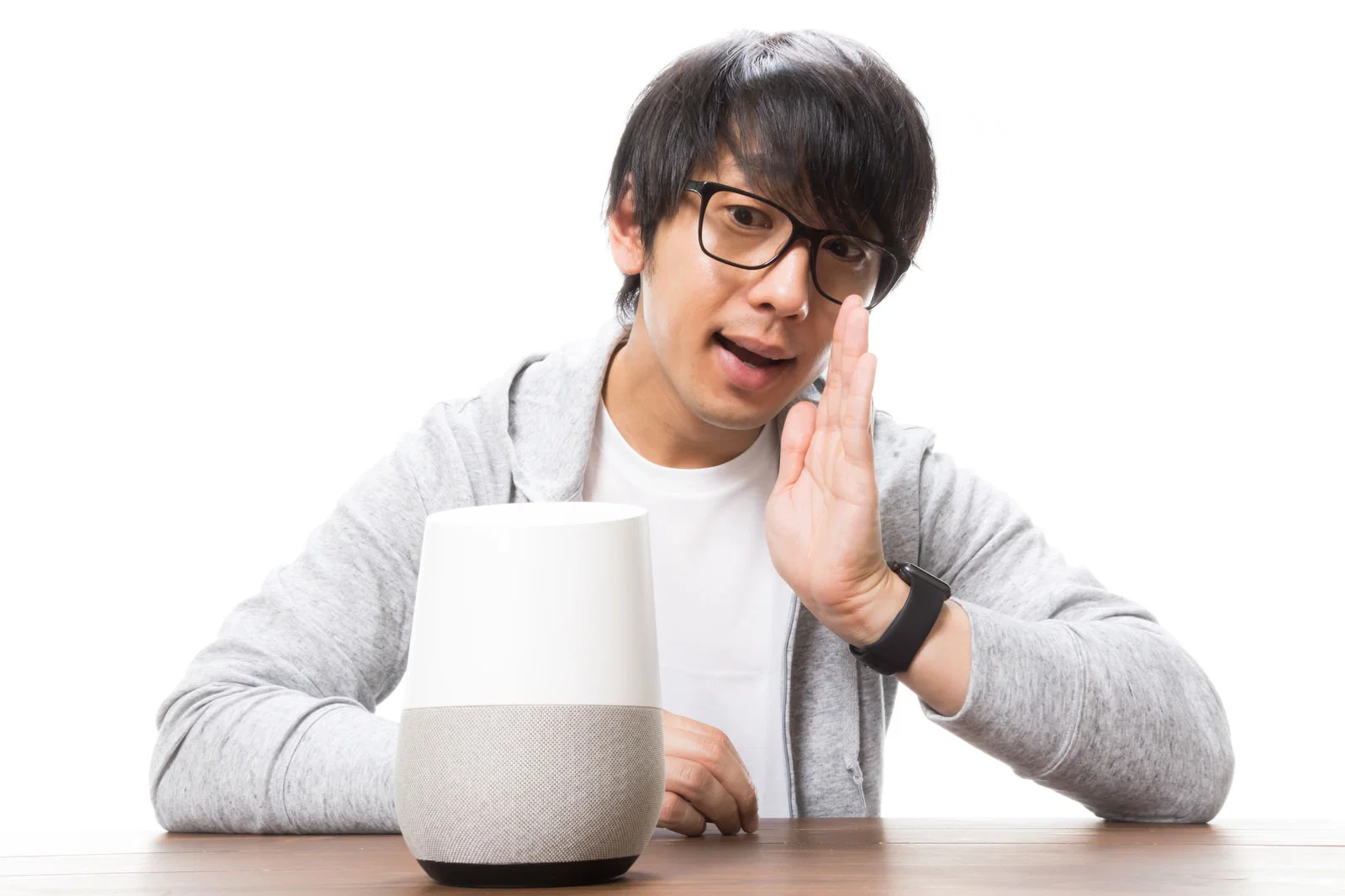 机上のスピーカーに手をかざして話しかける眼鏡の男性1人