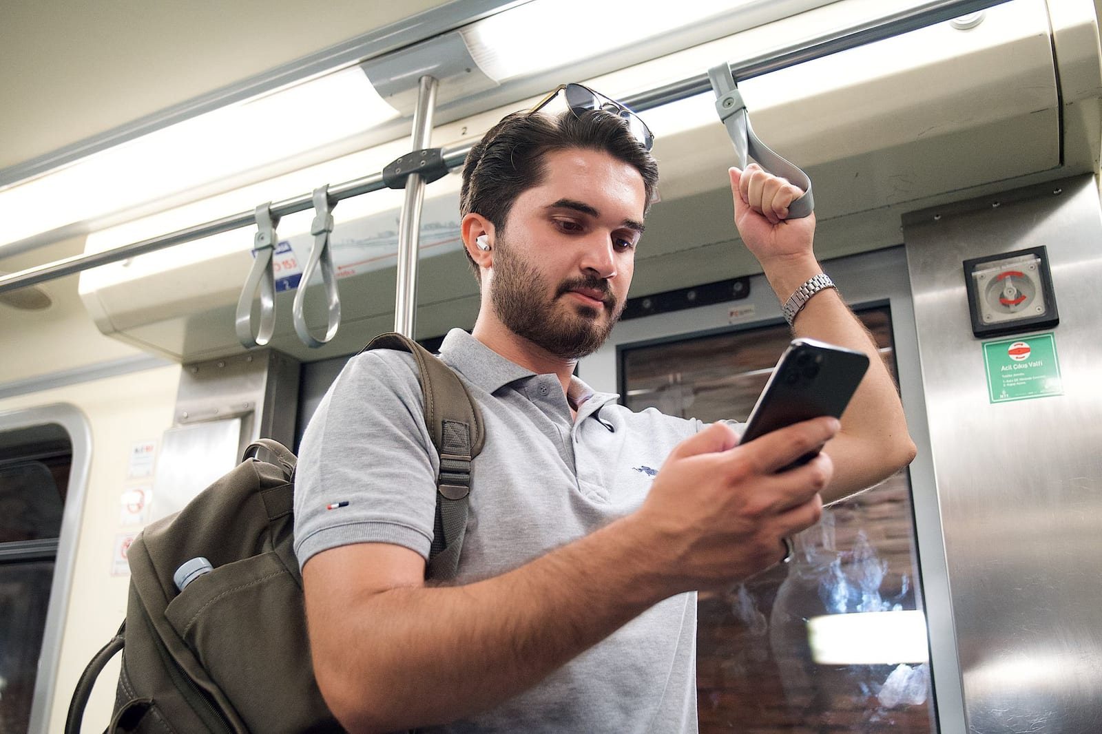 電車内で吊り革につかまりスマートフォンを見る男性1人の写真