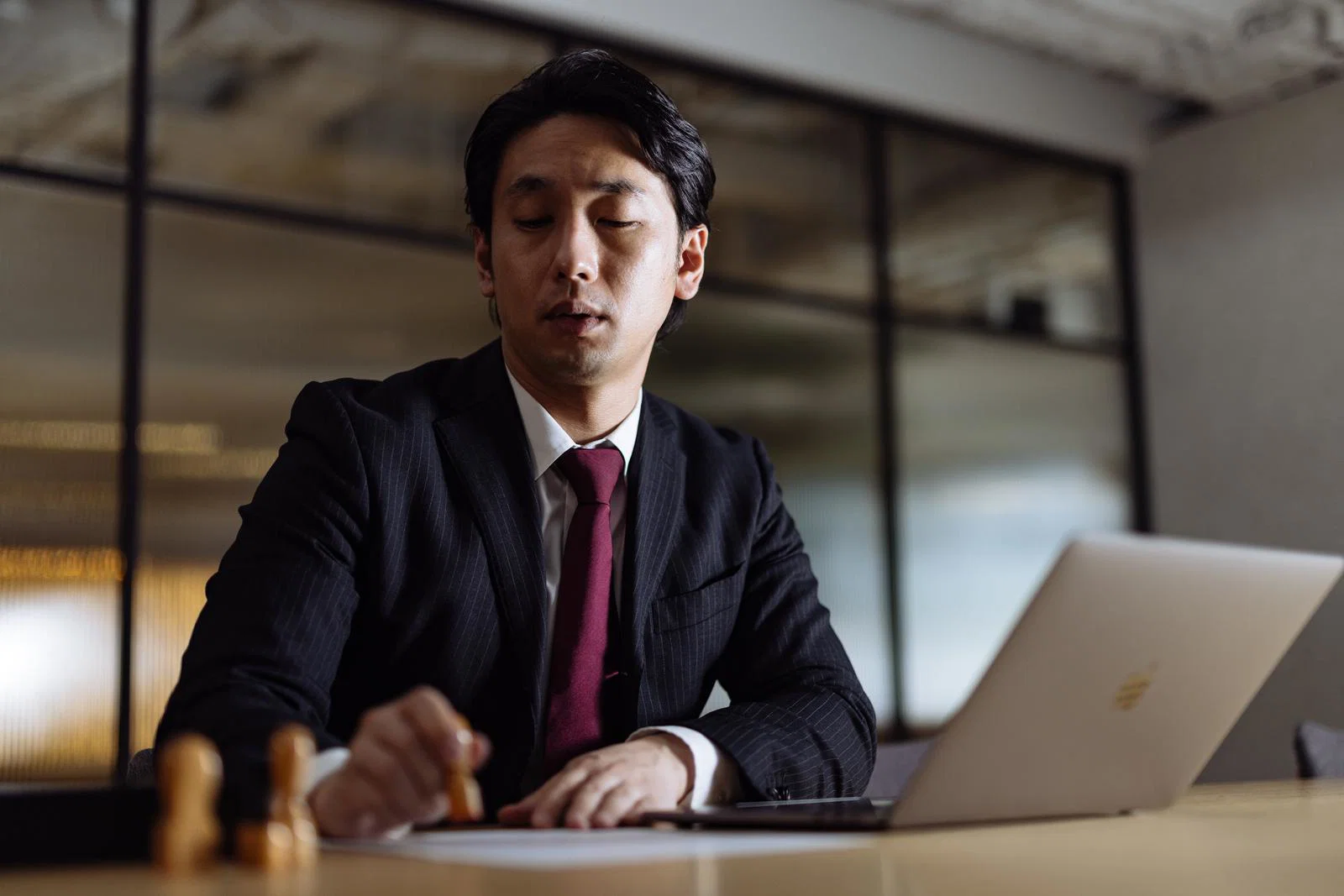 オフィスらしき屋内で、スーツ姿の男性一人がノートパソコン前で印鑑を持ち書類に押そうとしている様子
