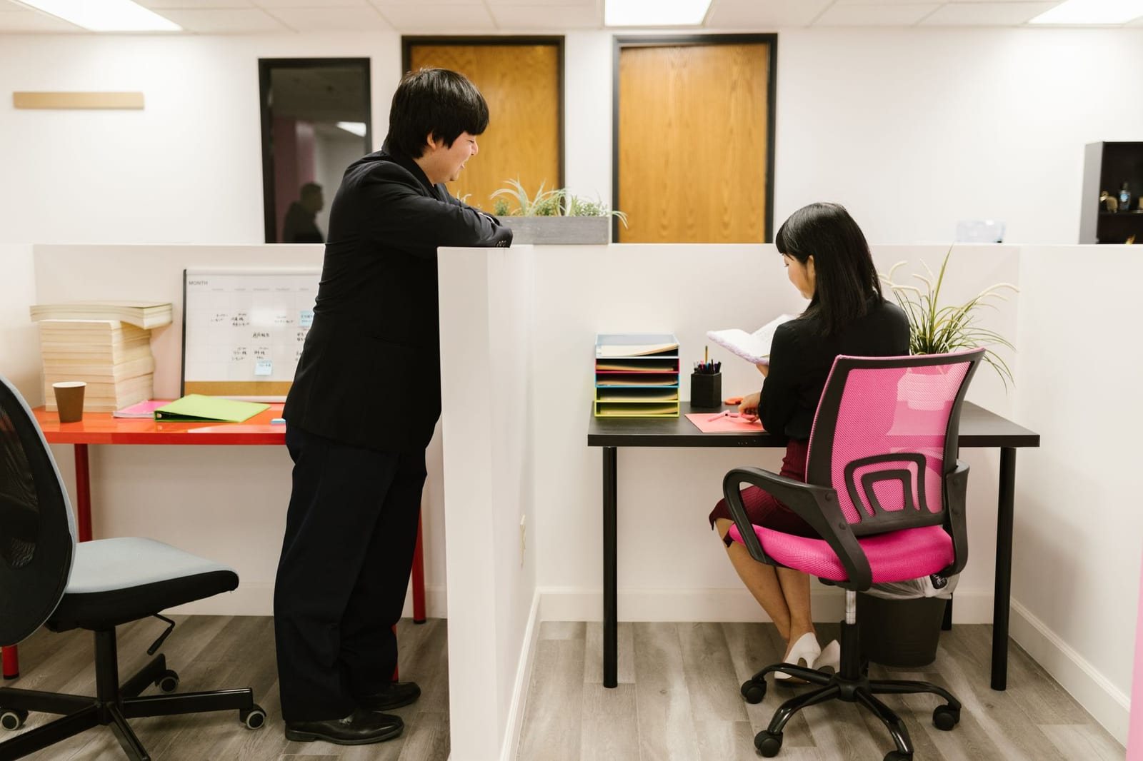 オフィスの仕切り越しに男女が向き合って会話する様子