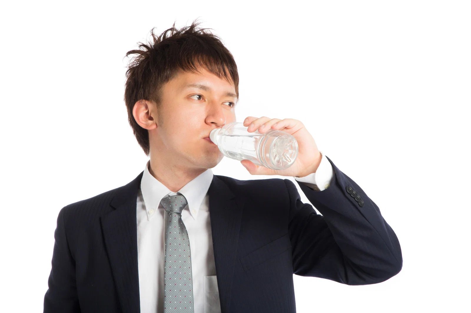 白背景でスーツ姿の男性1人がペットボトルの水を飲んでいる写真。