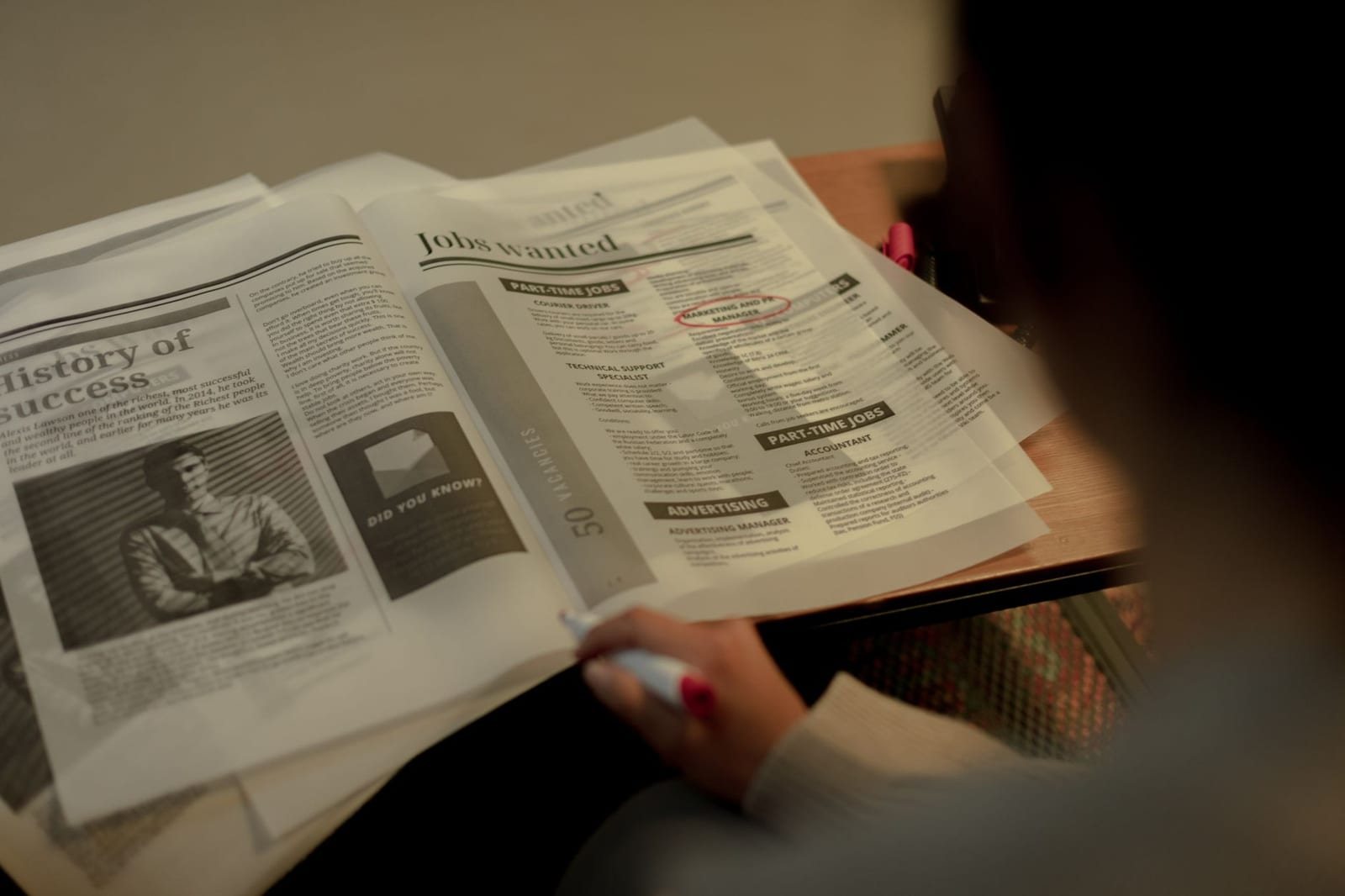 求人広告のページをペンで指しながら読む人物の手元