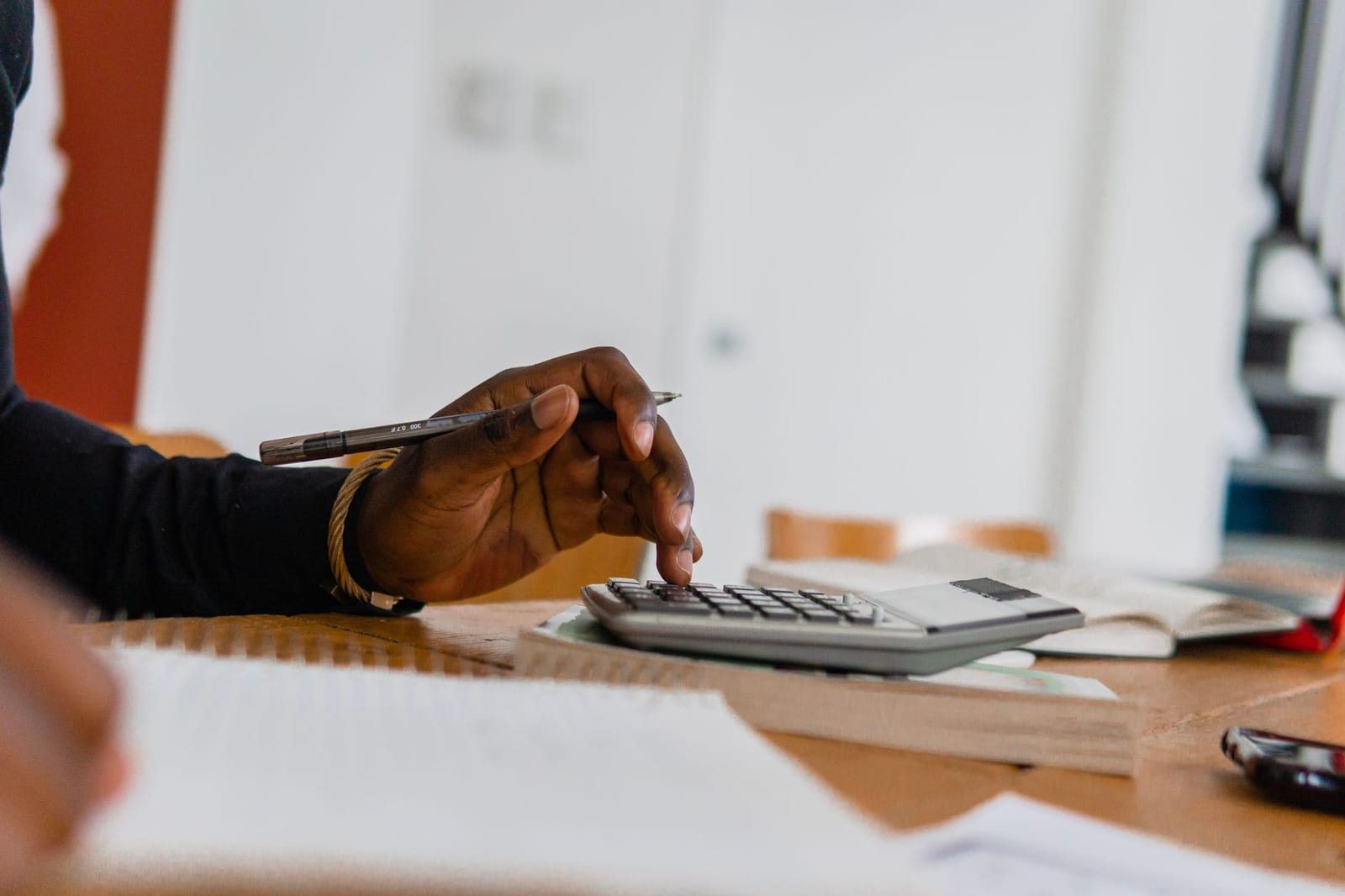 机上の電卓を指で操作する人物の手元アップ