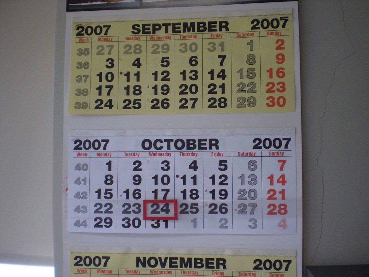 壁に貼られた9月と10月のカレンダーで24日が赤枠で囲まれている
