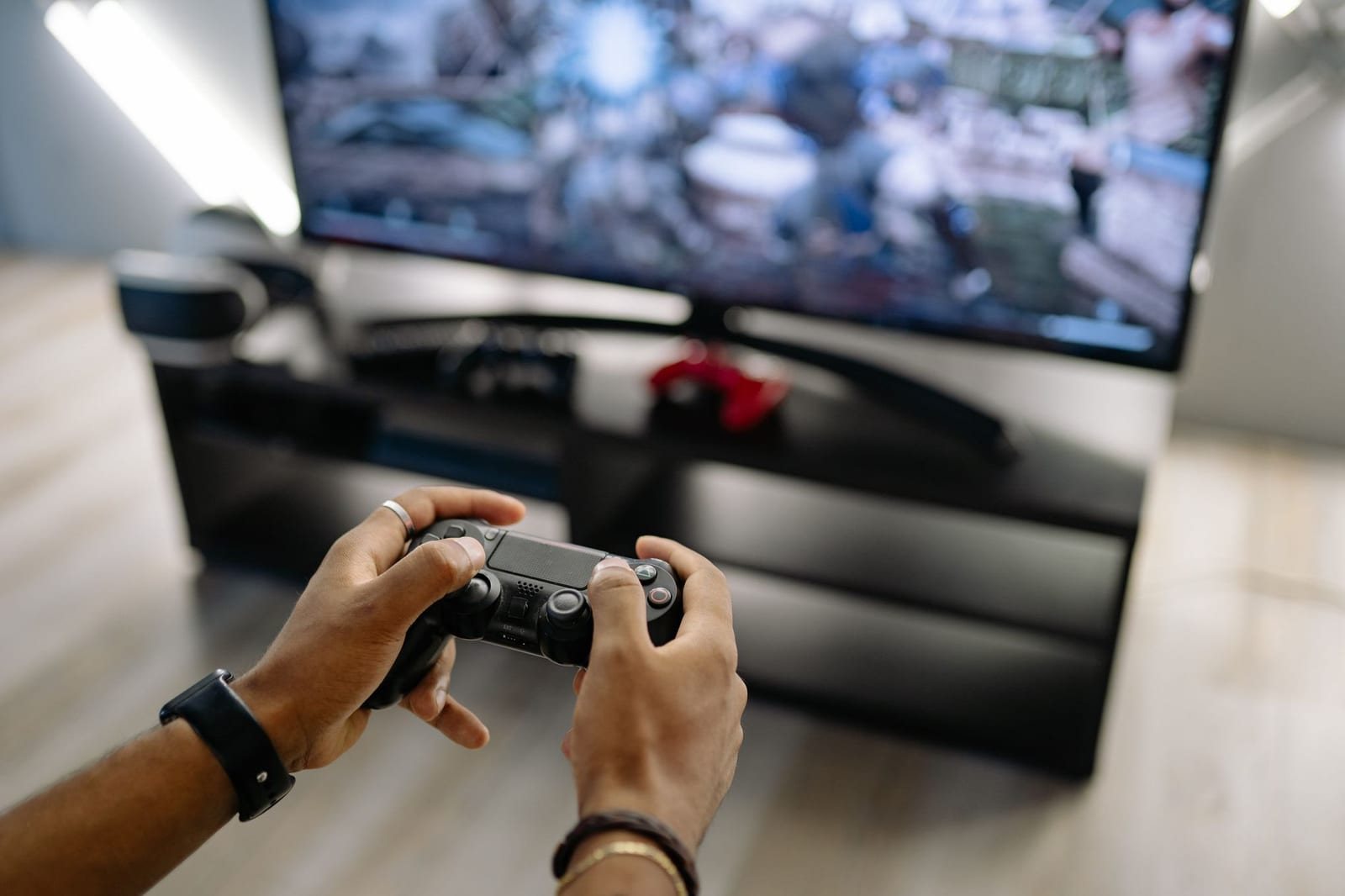 屋内でテレビ画面を見ながら両手でコントローラーを操作する人物