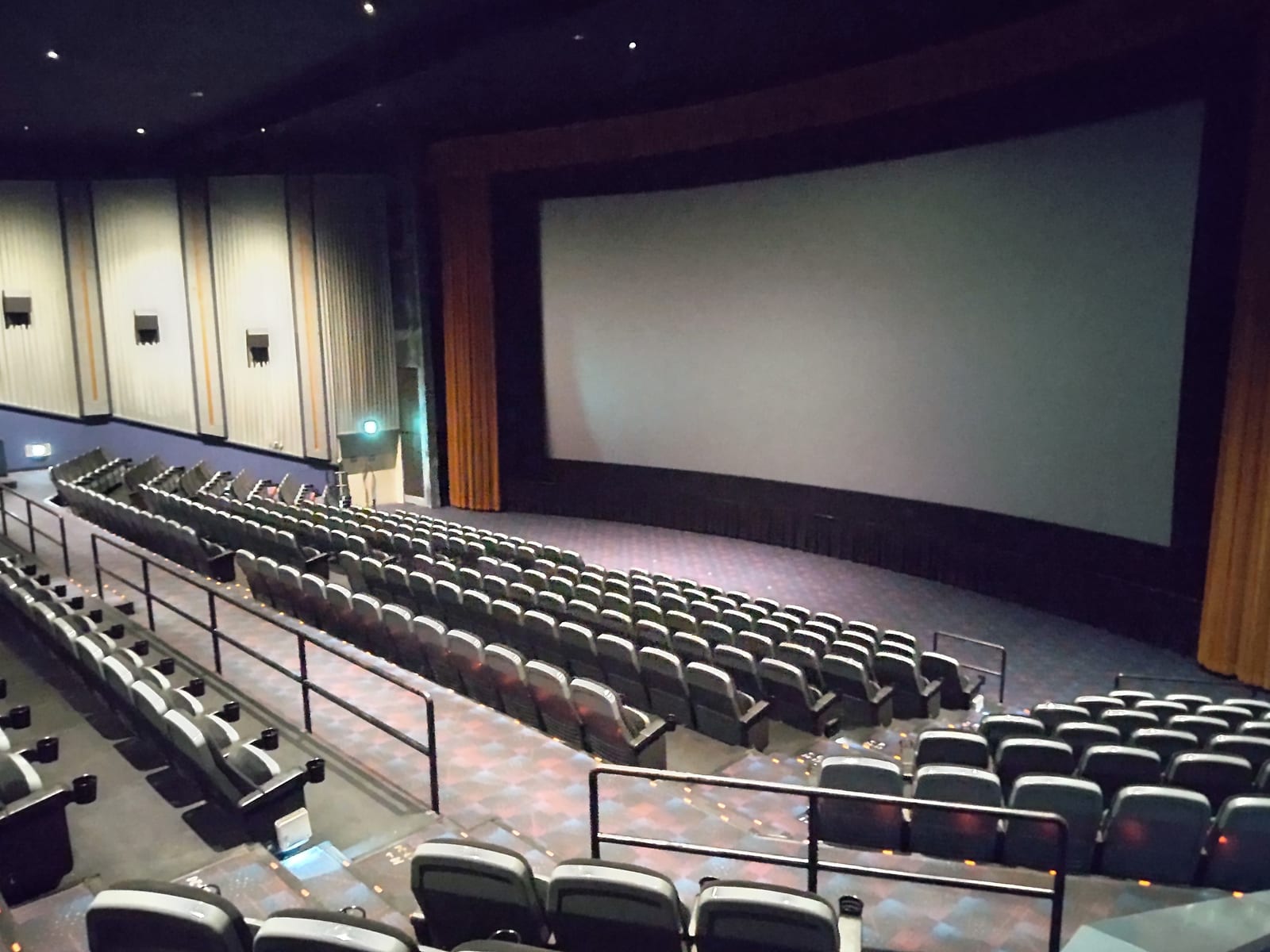 屋内の映画館スクリーン前、無人の座席が並ぶ客席全景