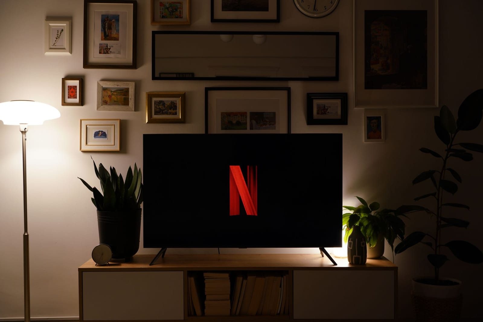 暗い家のリビングで壁掛けテレビにNetflixのロゴが表示された様子