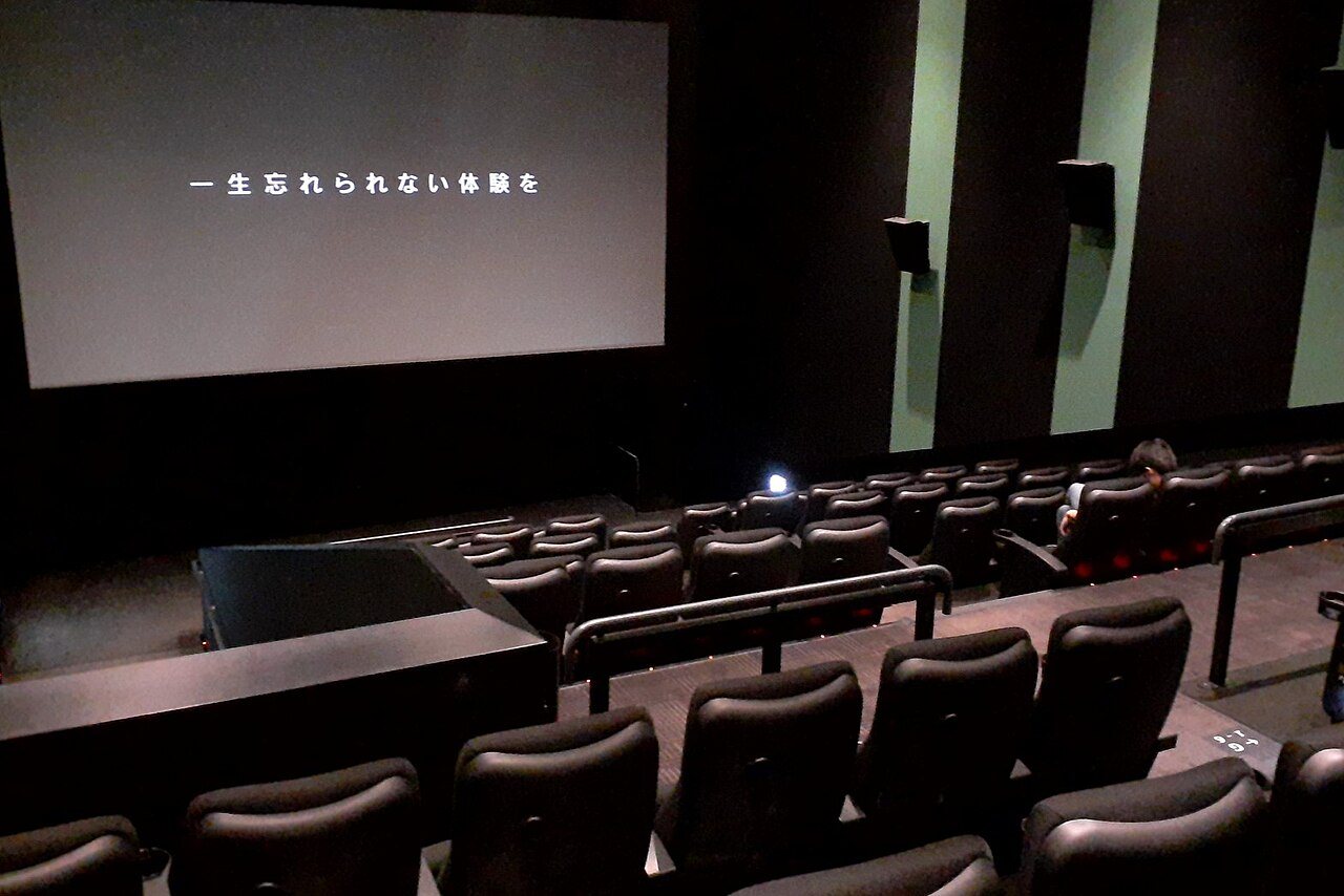 日本語字幕付きの暗い映画館で座席一人が座り開演前を待つ屋内写真