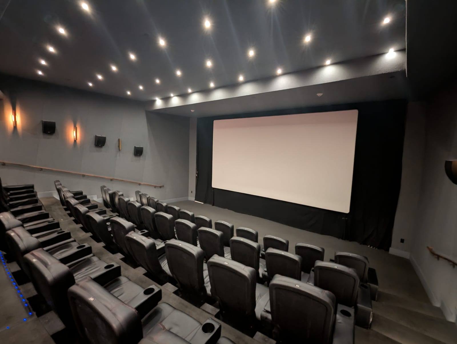 無人の映画館内に並ぶ座席と白いスクリーン