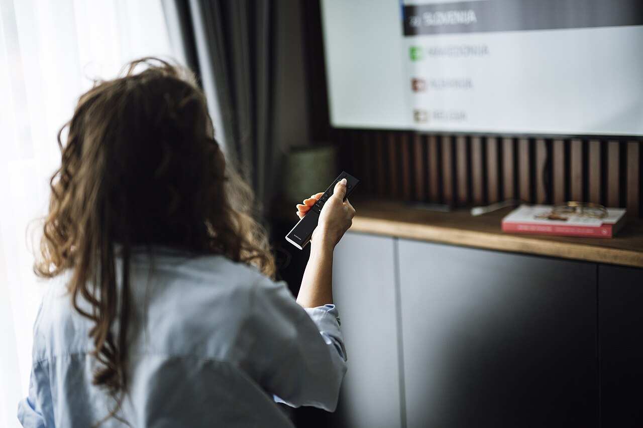 リモコンを持ちながらテレビを見る人物