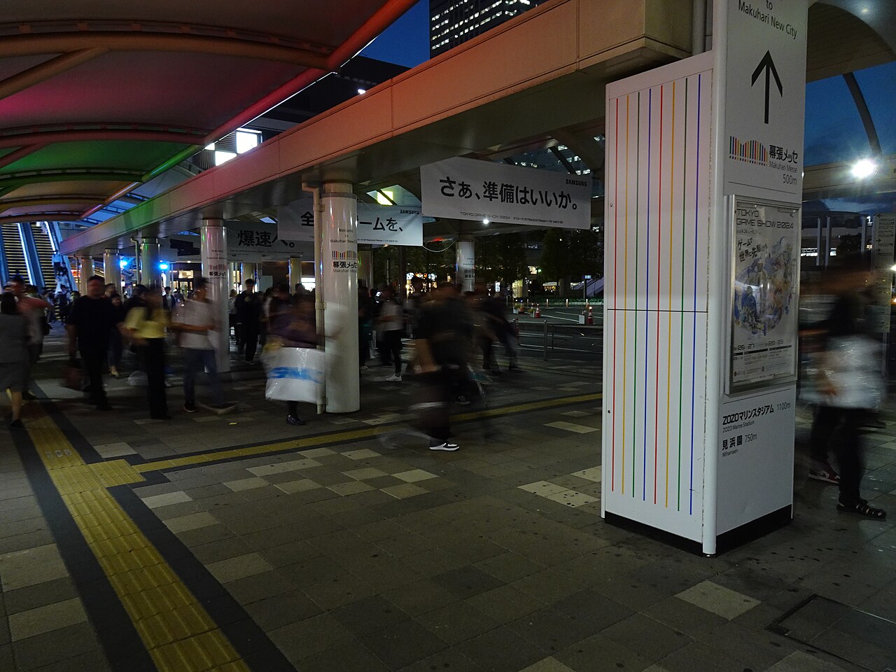 夜の屋根付き通路を大勢の人々が歩いている