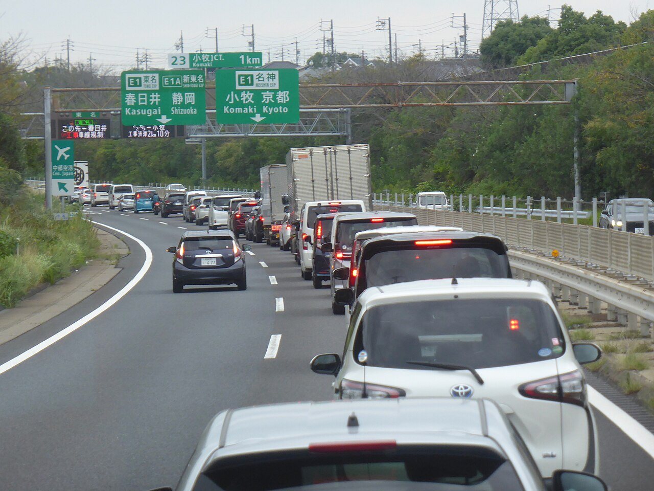 日本の高速道路で車列が停滞し前方に案内標識が並ぶ様子。