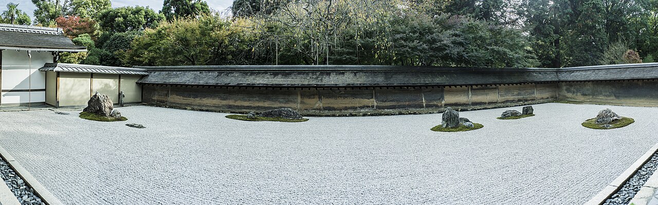土塀に囲まれた白砂と石組みが並ぶ無人の枯山水庭園