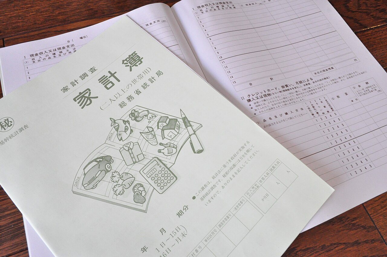 木製テーブルに置かれた総務省統計局の家計調査の家計簿冊子。