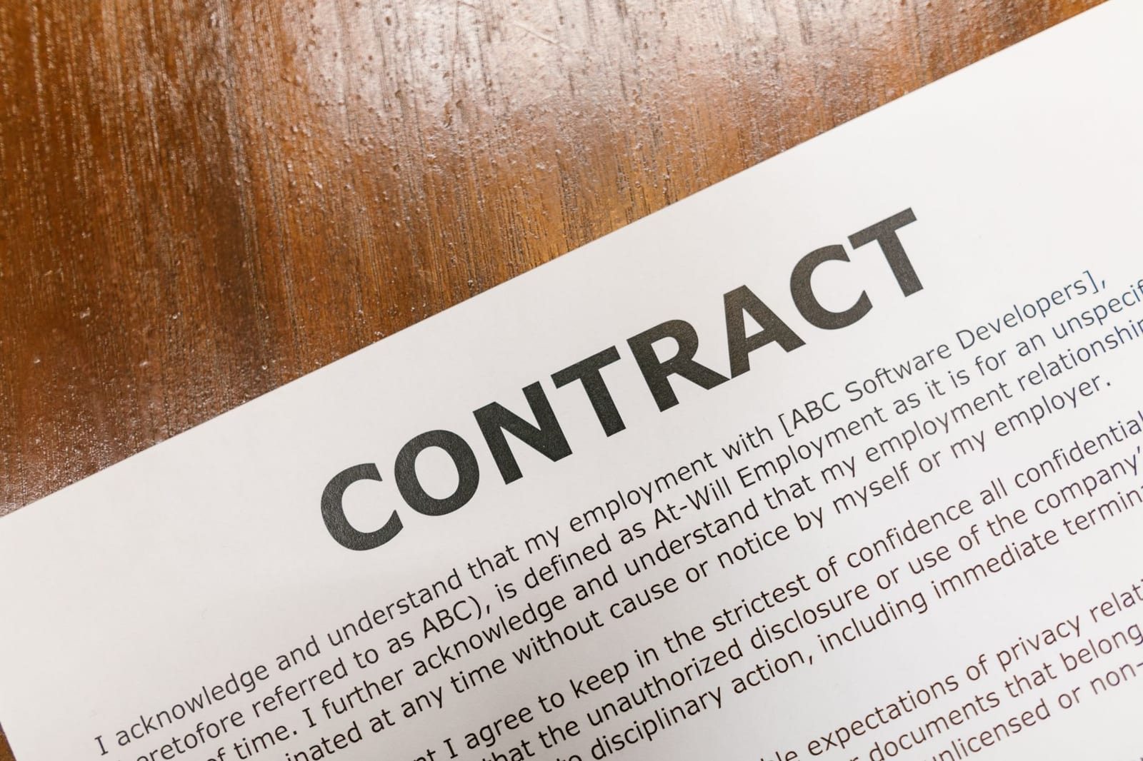 木の机に置かれた「CONTRACT」と印字された書類のアップ