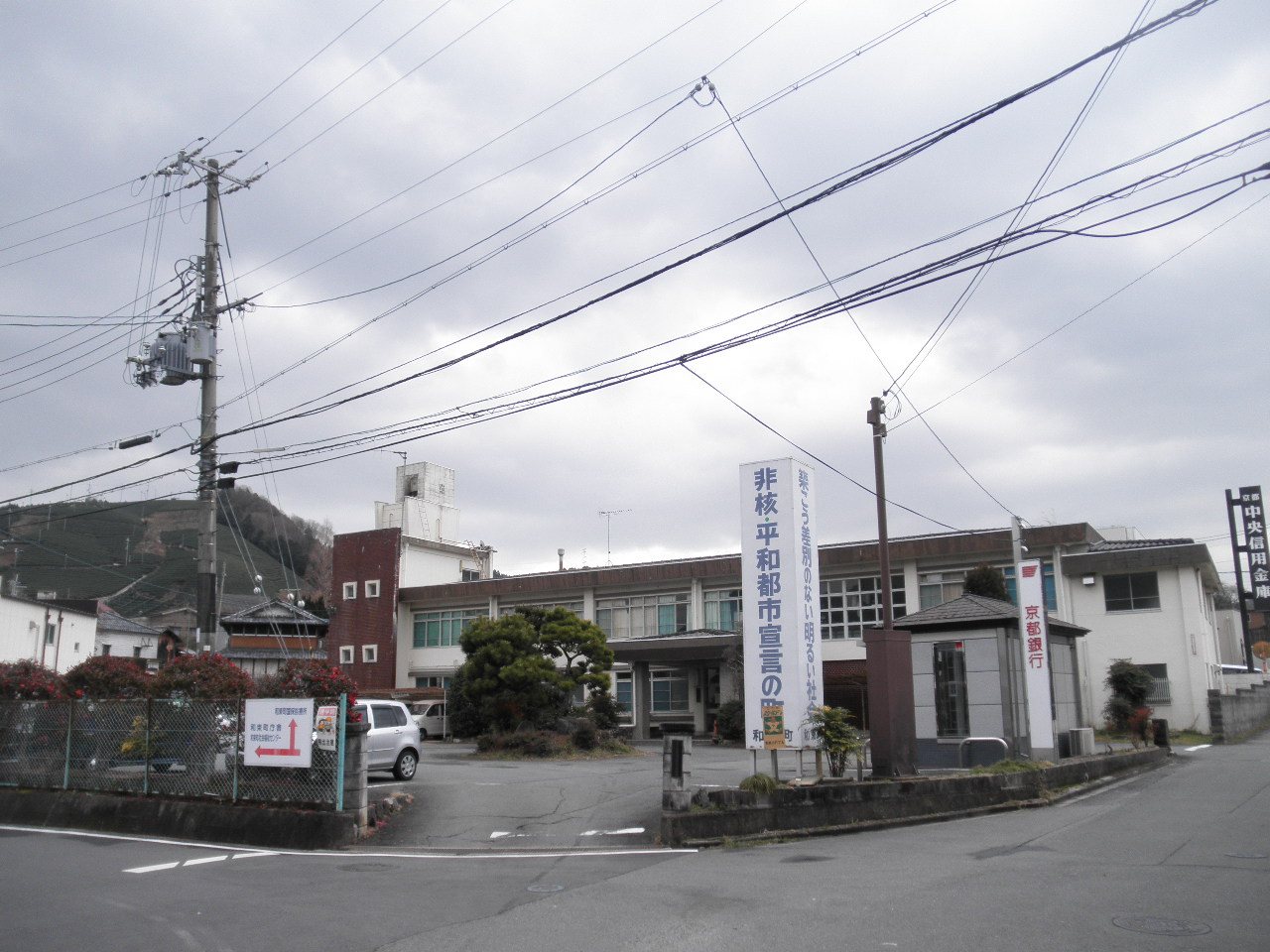 曇り空の下、看板や電線のある日本の町の役場前の道路