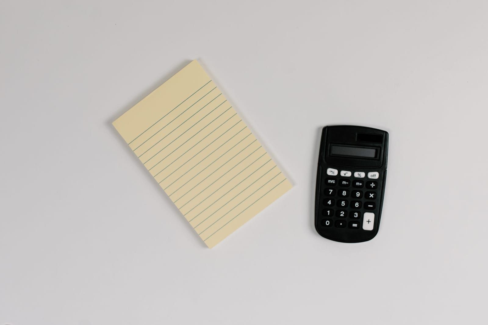 白い机の上のメモ帳と黒い電卓