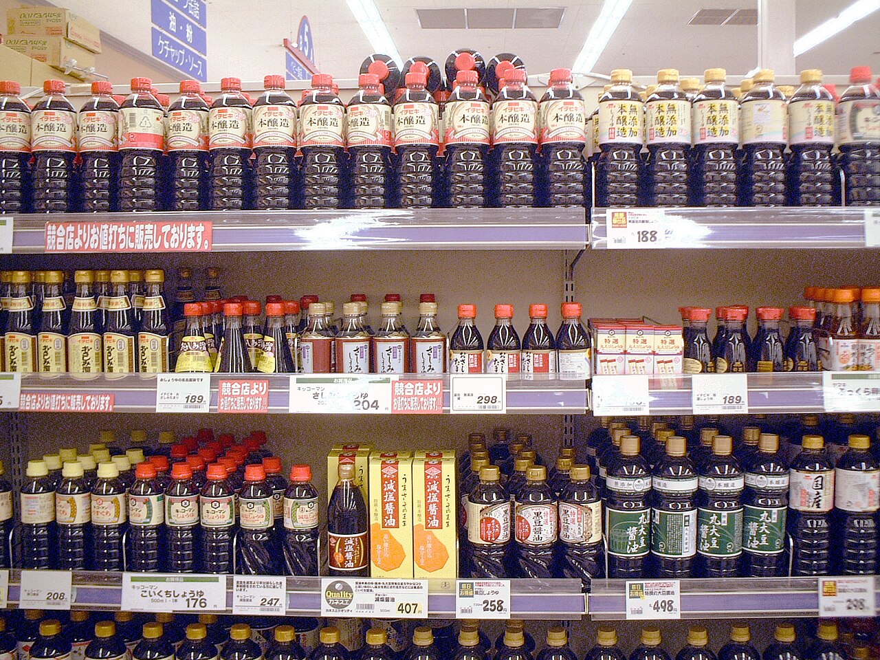 屋内スーパーの棚に醤油ボトルが大量に並び値札が付いている、人物なしの日本の店内写真