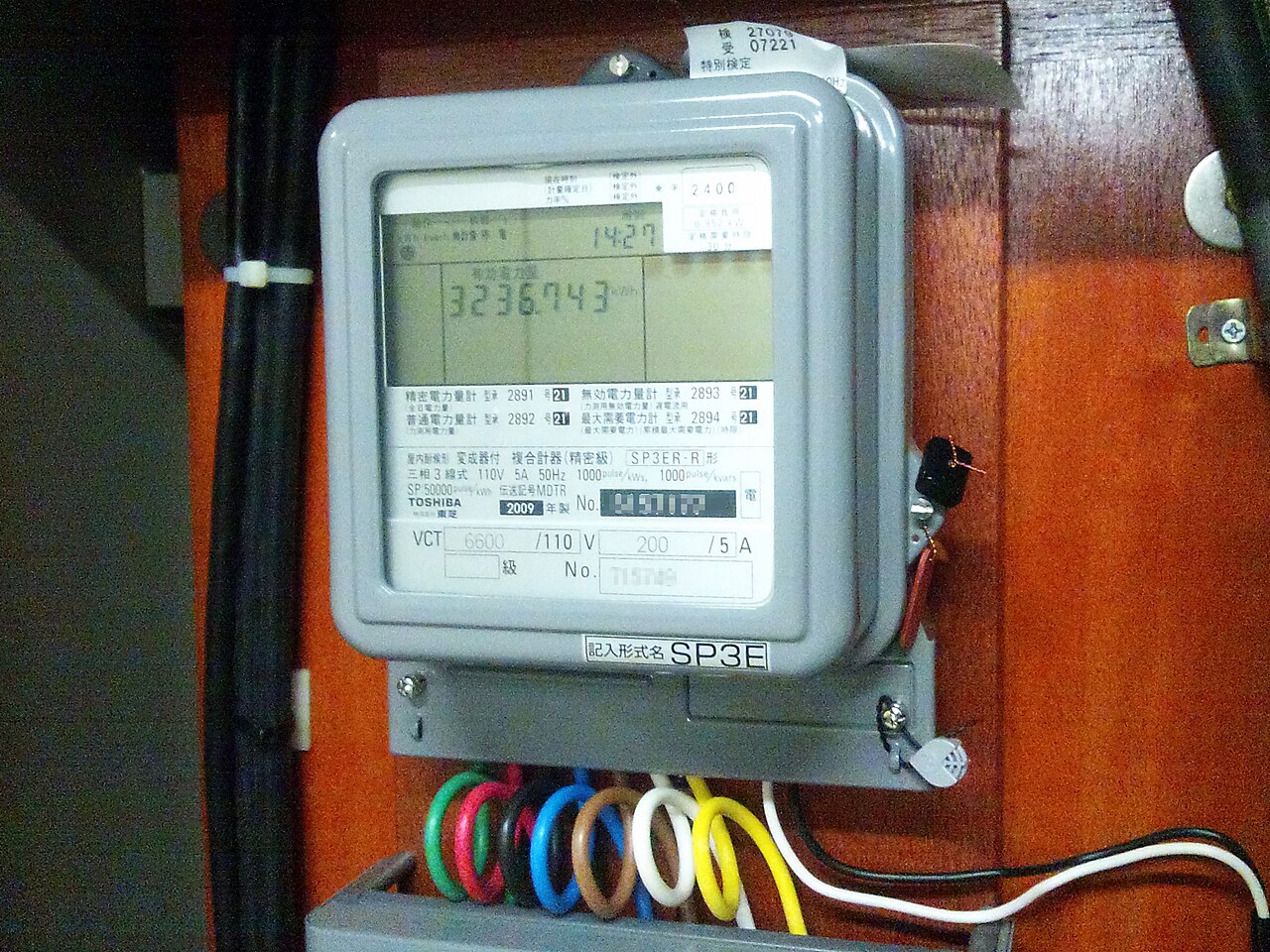 木製扉に設置された屋内用電力量メーターを近接撮影した写真