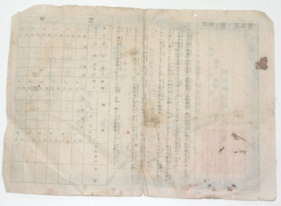 手書きの日本語と朱印のある古びたしみだらけの証書用紙を撮った写真、人物なし。