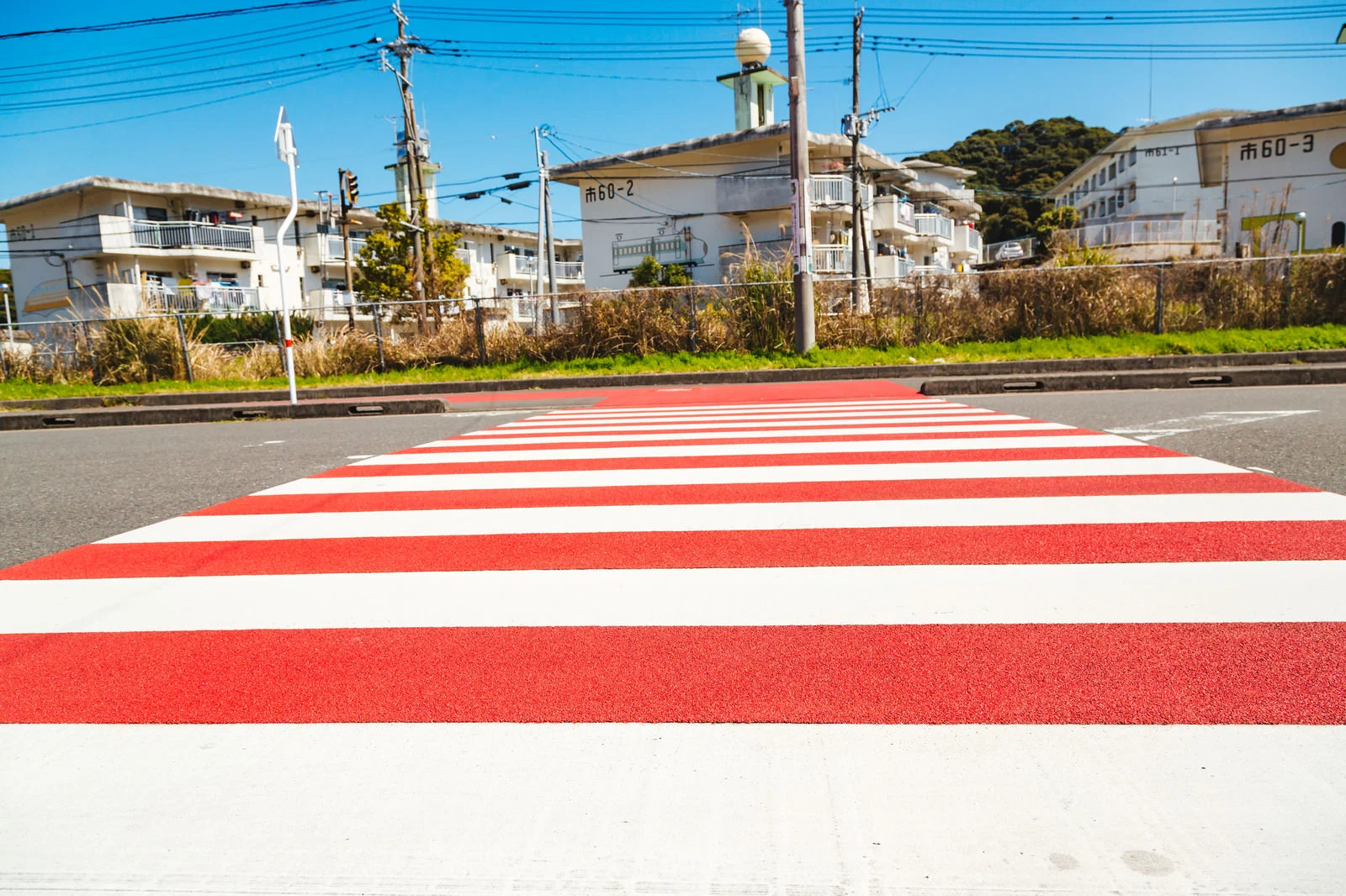 無人の住宅街の道路にある赤白の横断歩道を近くから撮影した写真