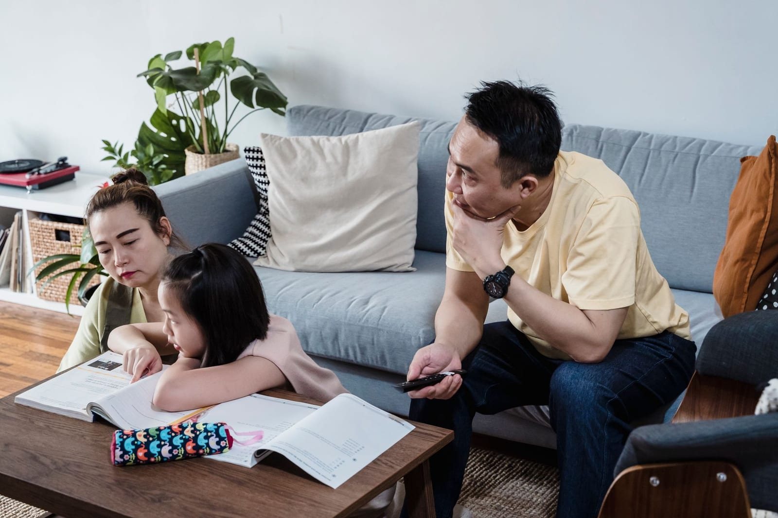 リビングのソファ前で両親と子供がテーブルの本を見ている様子