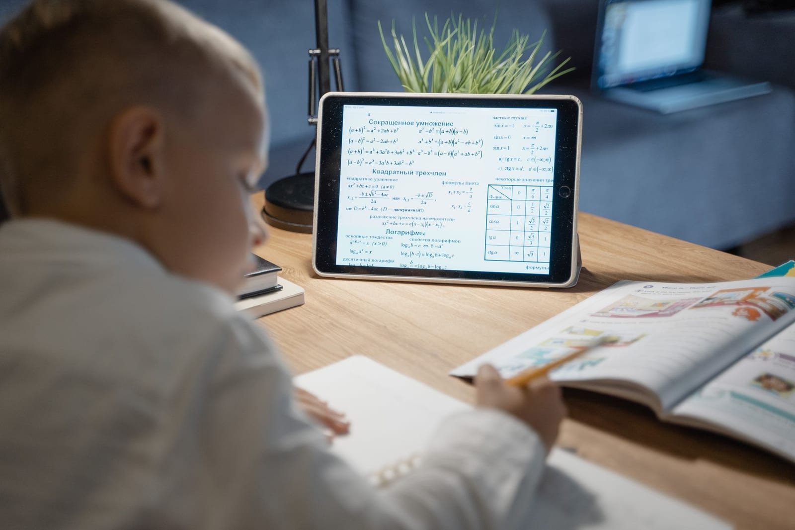 室内の机でタブレット画面の数式を見ながら勉強する子ども1人