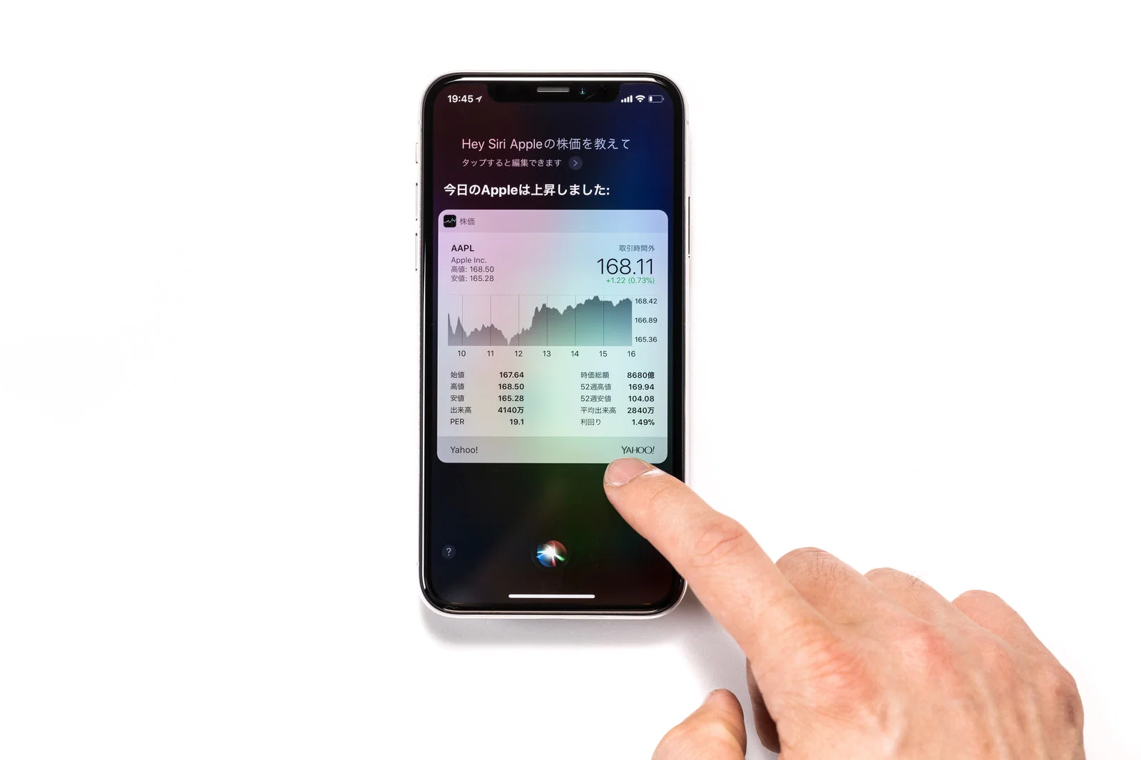 屋内で1人がスマートフォンのSiri株価画面を指で操作している様子