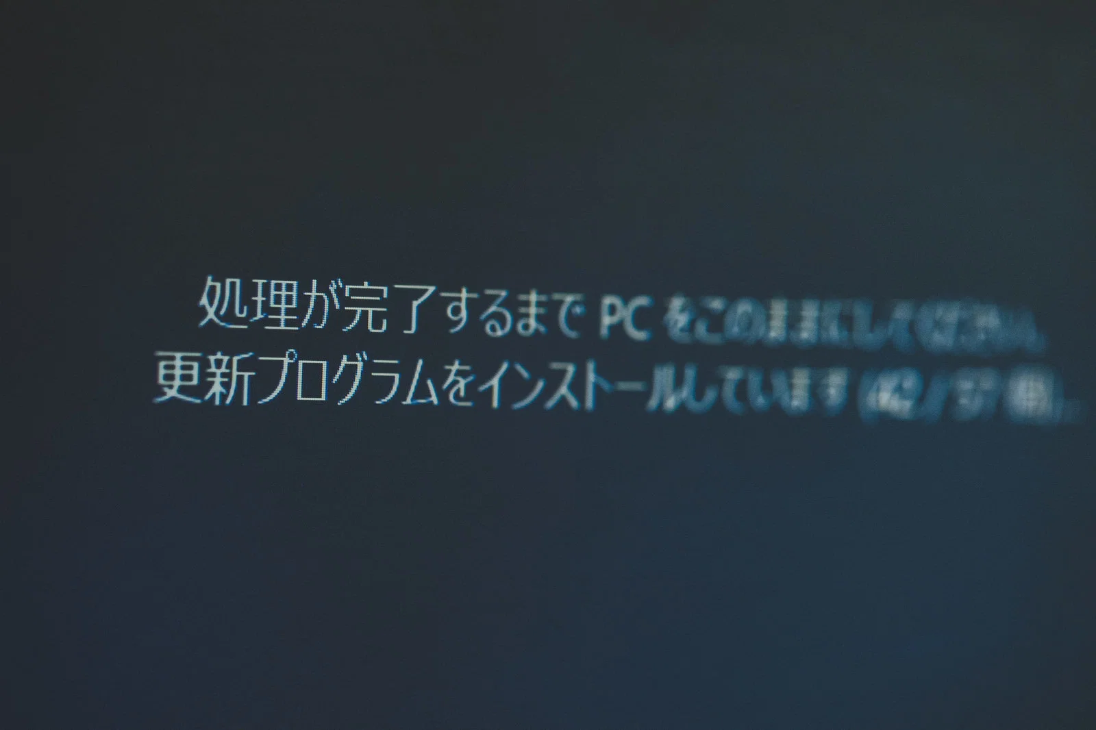 PC画面に更新プログラムのインストール中を示す青いメッセージが表示されている