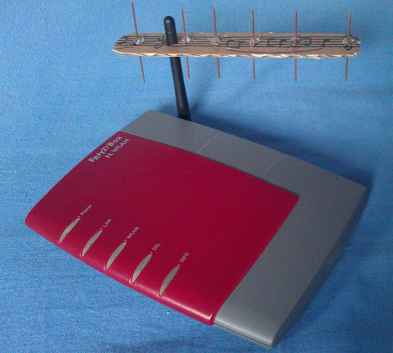 屋内で青い布の上に置かれた赤色のWi-Fiルーターと自作アンテナ