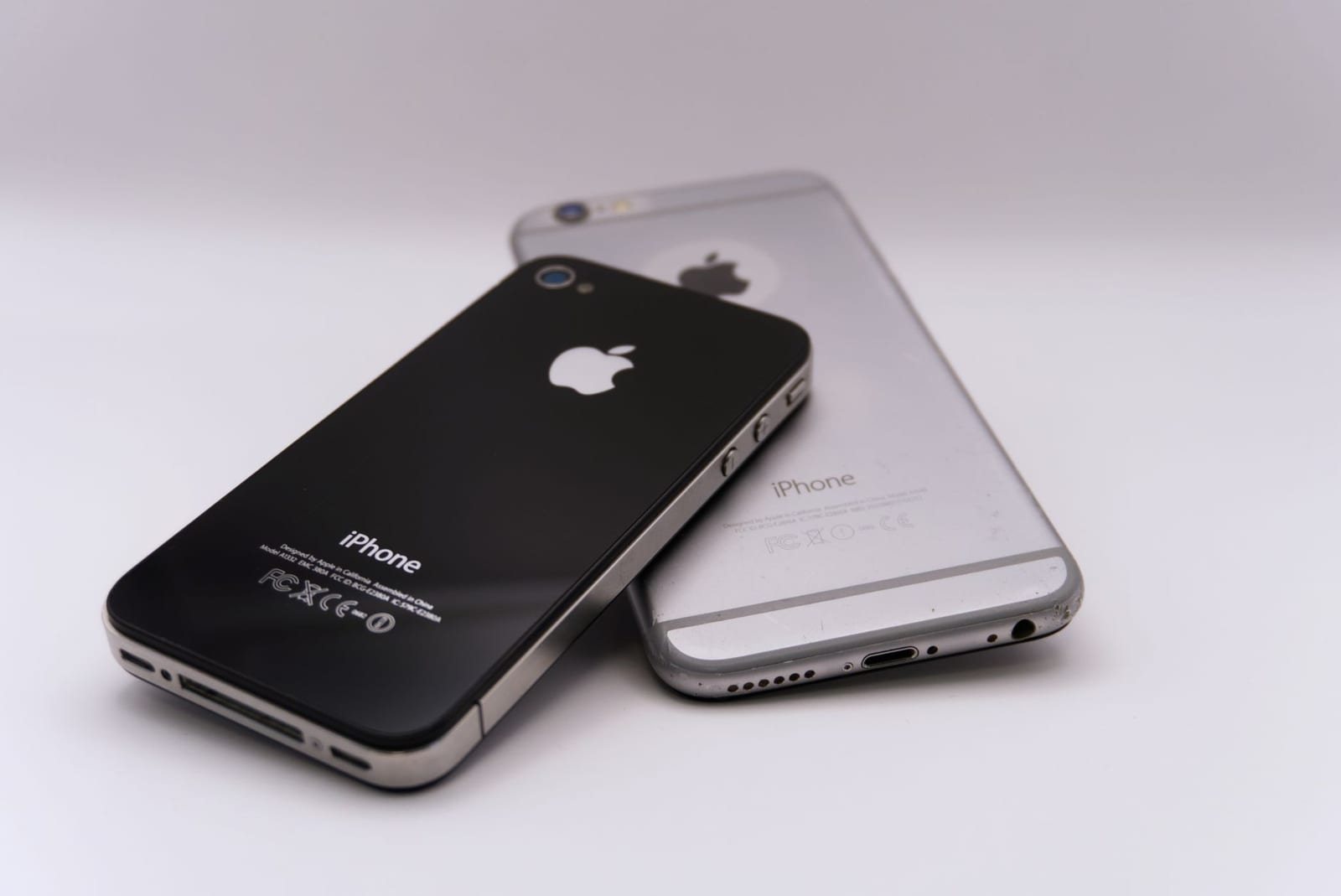 白背景に重ねて置かれた黒と白2台のiPhone背面