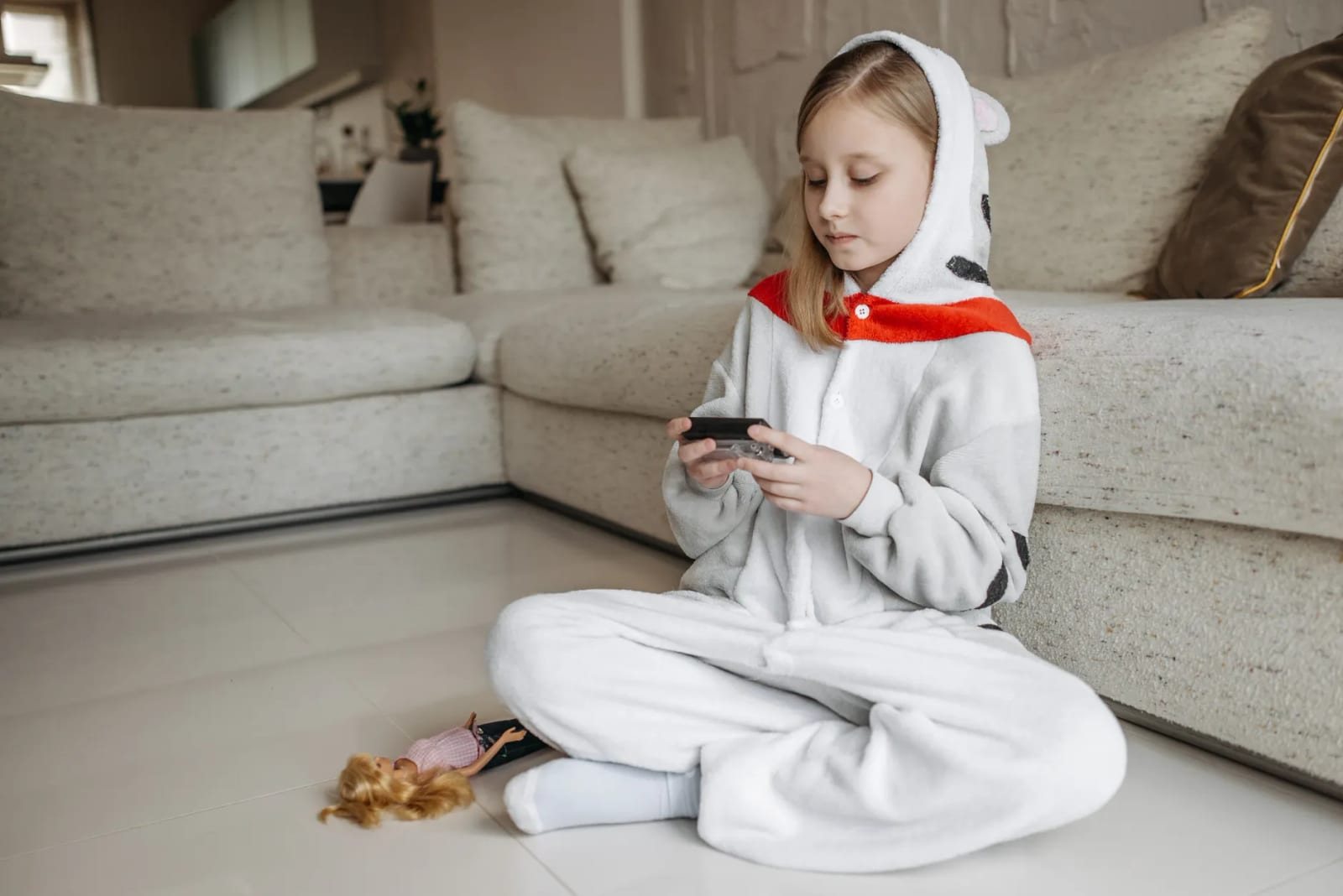 室内のソファ前で着ぐるみパジャマの少女1人がスマホを操作する写真