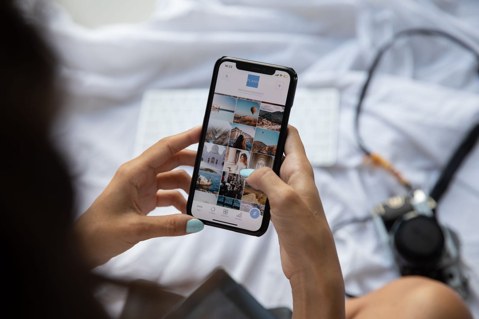 ベッドの上でカメラのそばに座りスマホで写真アプリを操作する人物