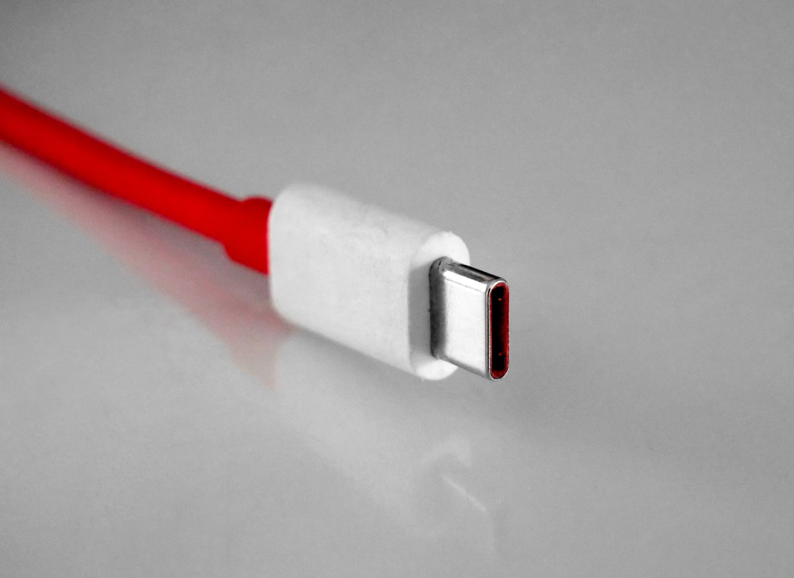 灰色の背景に赤いケーブルとUSB-Cコネクタ先端をアップで撮影した写真。