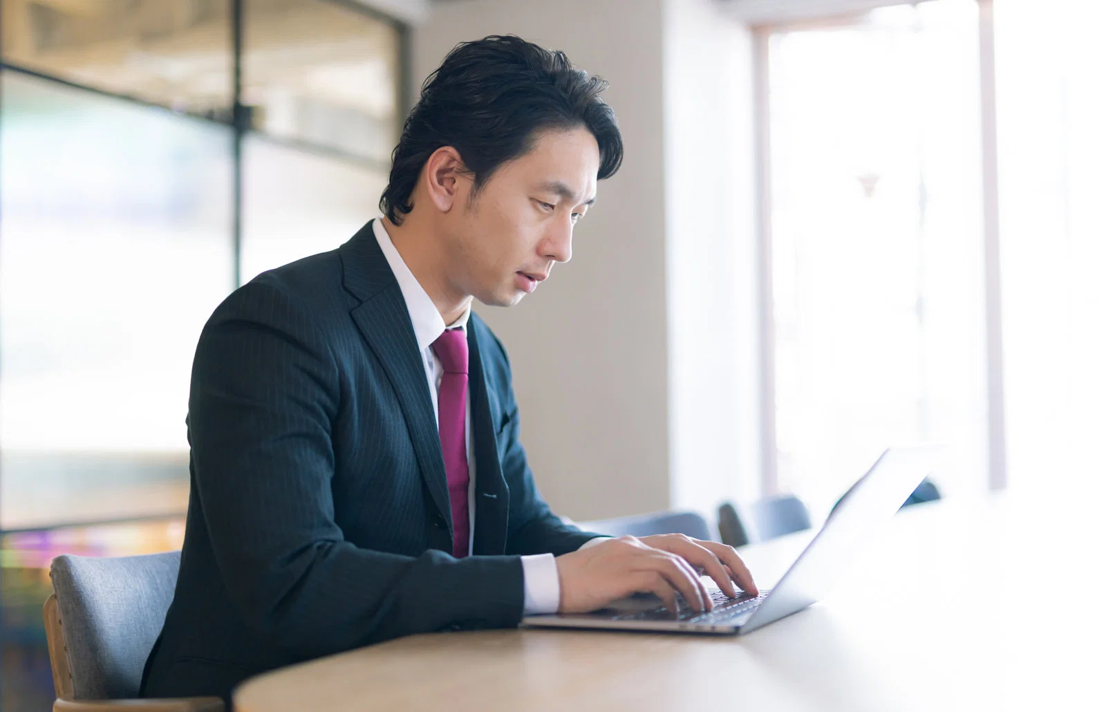 屋内オフィスで男性1人がノートPCをキーボード入力している様子